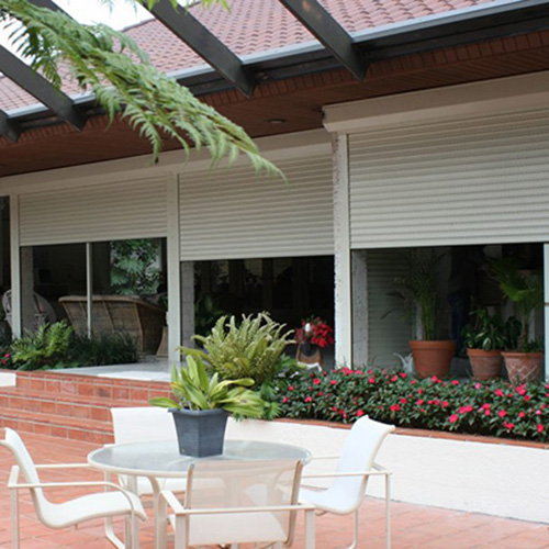 partially closed floor-to-ceiling white rollups over patio windows in home backyard.